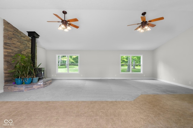 12383 S 25 W, Columbus, IN 47201 - unfurnished living room featuring a wood stove, carpet floors, vaulted ceiling, ceiling fan, and healthy amount of natural light
