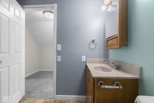 12383 S 25 W, Columbus, IN 47201 - bathroom with vanity, toilet, vaulted ceiling, a textured ceiling, and baseboards