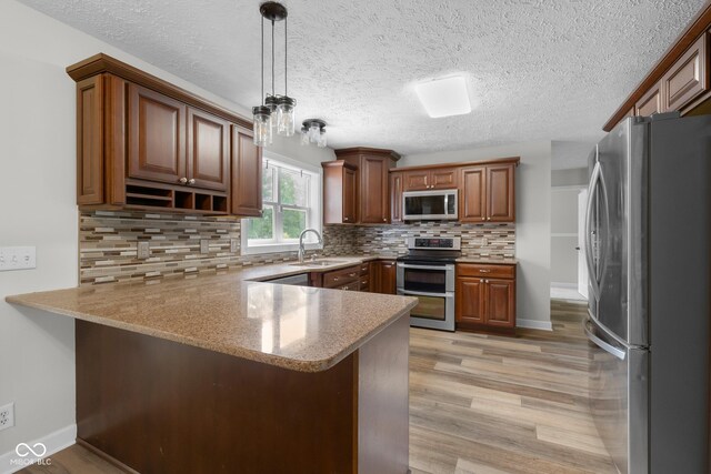 12383 S 25 W, Columbus, IN 47201 - kitchen with appliances with stainless steel finishes, a peninsula, a sink, light wood-style flooring, and backsplash