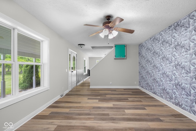 12383 S 25 W, Columbus, IN 47201 - spare room featuring wallpapered walls, a ceiling fan, baseboards, wood finished floors, and an accent wall