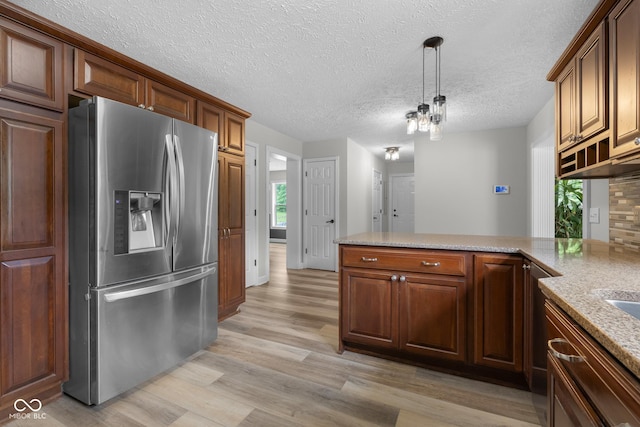 12383 S 25 W, Columbus, IN 47201 - kitchen featuring stainless steel refrigerator with ice dispenser, light wood finished floors, a peninsula, hanging light fixtures, and a textured ceiling