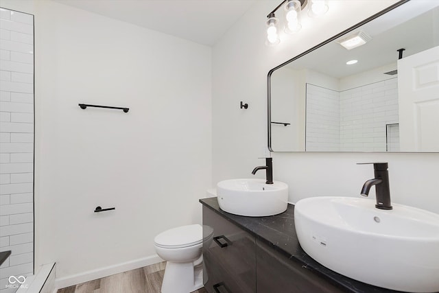 233 N Devon Ave, Indianapolis, IN 46219 - full bathroom featuring wood finished floors, double vanity, a tile shower, toilet, and baseboards