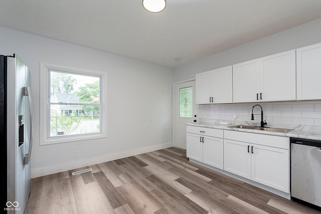 2531 E Brookside Ave, Indianapolis, IN 46218 - kitchen featuring a sink, stainless steel appliances, decorative backsplash, light wood finished floors, and baseboards