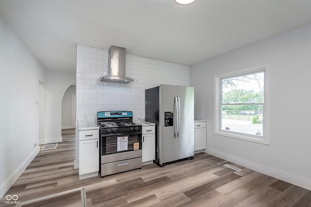 2531 E Brookside Ave, Indianapolis, IN 46218 - kitchen with appliances with stainless steel finishes, wall chimney exhaust hood, light countertops, light wood-style flooring, and white cabinets