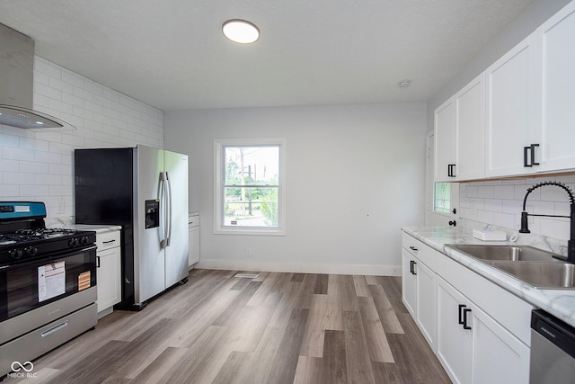 2531 E Brookside Ave, Indianapolis, IN 46218 - kitchen featuring stainless steel appliances, wall chimney exhaust hood, a sink, decorative backsplash, and white cabinets