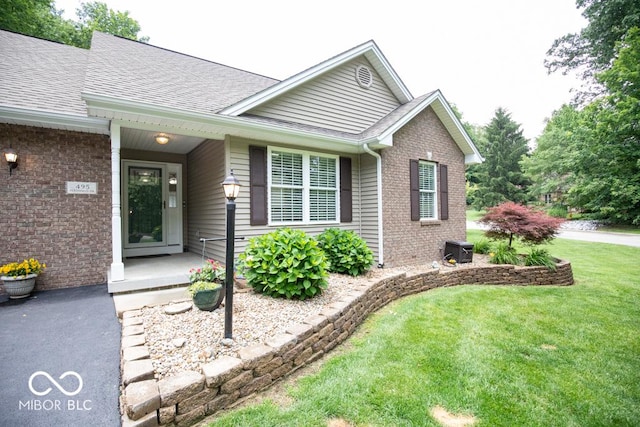 495 Persimmon Dr, North Vernon, IN 47265 - view of front of house with brick siding, roof with shingles, a front lawn, and cooling unit