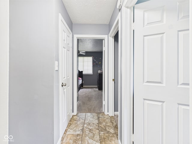 3223 Keystone Lakes Way, Indianapolis, IN 46237 - hallway featuring a textured ceiling, baseboards, and light carpet