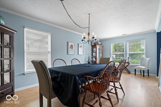 12624 Majestic Way, Fishers, IN 46037 - dining area featuring crown molding, a textured ceiling, light wood-style floors, a chandelier, and baseboards