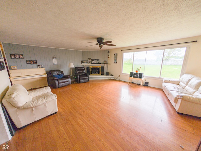 2612 E Michigantown Rd, Frankfort, IN 46041 - living area with ceiling fan, a textured ceiling, wood finished floors, a glass covered fireplace, and wooden walls