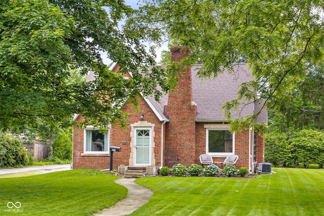 2645 Washington St, Columbus, IN 47201 - tudor home with a front yard, a chimney, brick siding, and central AC unit