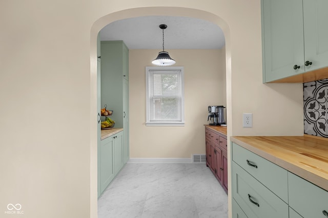 2645 Washington St, Columbus, IN 47201 - kitchen with arched walkways, light marble finish flooring, wooden counters, baseboards, and hanging light fixtures