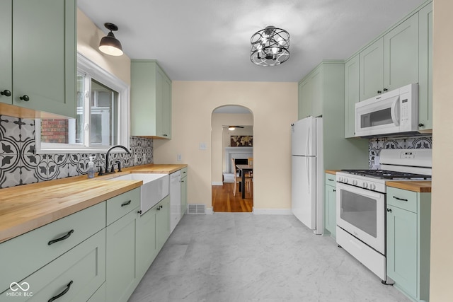 2645 Washington St, Columbus, IN 47201 - kitchen with white appliances, butcher block countertops, green cabinetry, arched walkways, and backsplash