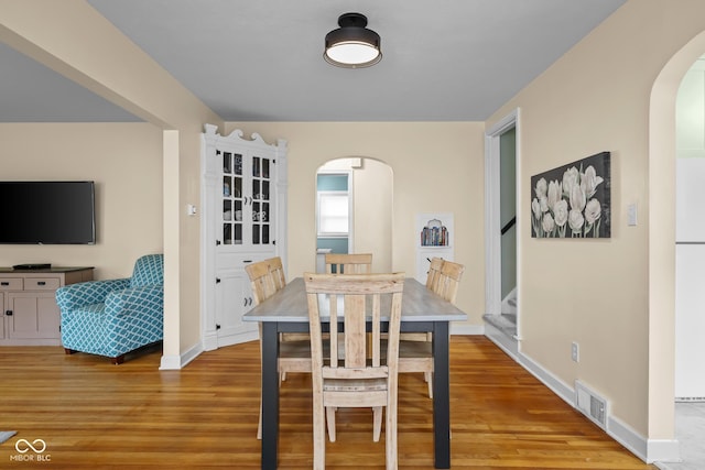 2645 Washington St, Columbus, IN 47201 - dining room featuring arched walkways, light wood finished floors, stairs, and baseboards