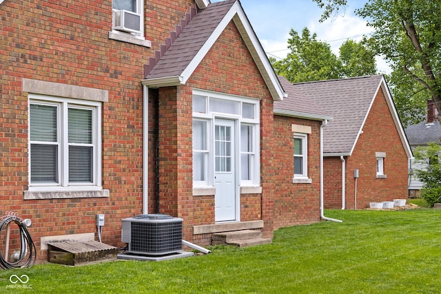 2645 Washington St, Columbus, IN 47201 - view of side of property with central air condition unit, entry steps, a yard, brick siding, and a shingled roof