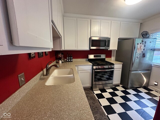 5147 E 16th St, Indianapolis, IN 46218 - kitchen featuring stainless steel appliances, a sink, white cabinets, tile patterned floors, and crown molding