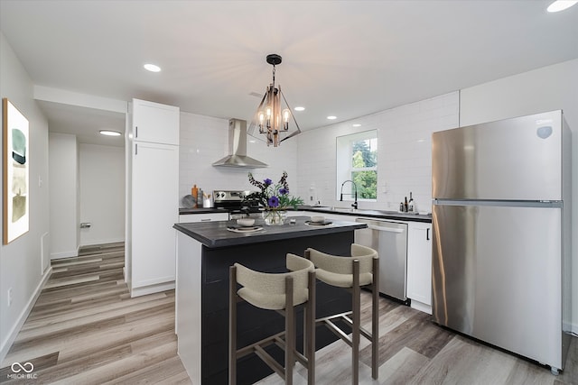 2631 Collier St, Indianapolis, IN 46241 - kitchen featuring appliances with stainless steel finishes, wall chimney exhaust hood, dark countertops, light wood-style flooring, and decorative backsplash