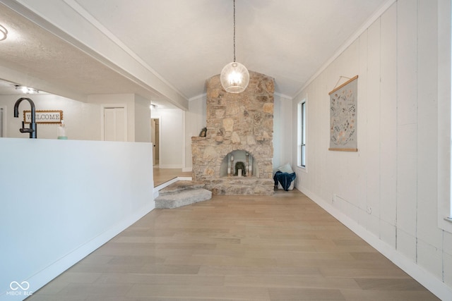 1127 Hickory Ln, New Castle, IN 47362 - unfurnished living room with lofted ceiling, light wood-style flooring, a stone fireplace, and ornamental molding