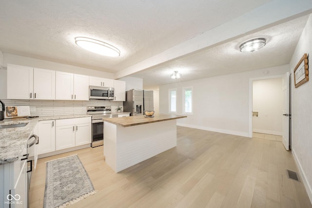1127 Hickory Ln, New Castle, IN 47362 - kitchen with stainless steel appliances, a textured ceiling, backsplash, a center island, and butcher block counters