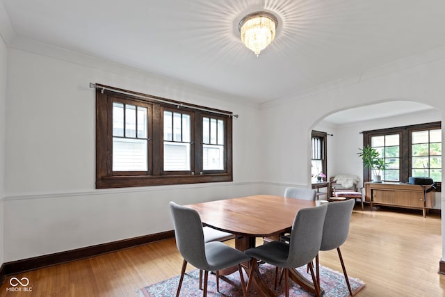 5259 Broadway St, Indianapolis, IN 46220 - dining space with arched walkways, a chandelier, crown molding, light wood-style flooring, and baseboards