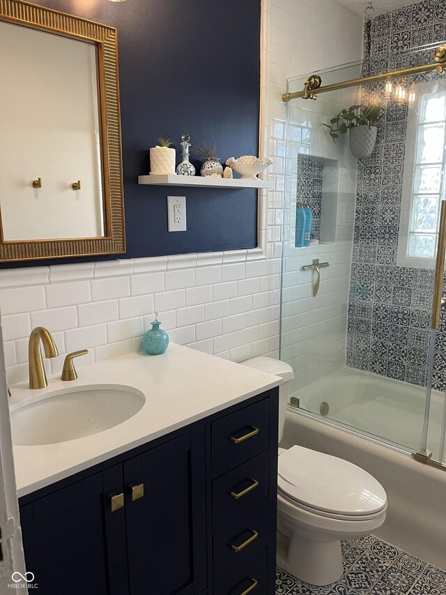 5259 Broadway St, Indianapolis, IN 46220 - bathroom with tile walls, vanity, bath / shower combo with glass door, toilet, and tile patterned floors