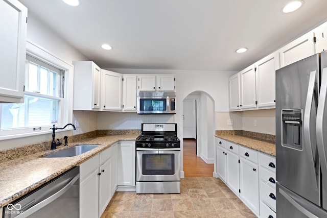 5259 Broadway St, Indianapolis, IN 46220 - kitchen featuring stainless steel appliances, a sink, arched walkways, white cabinetry, and recessed lighting