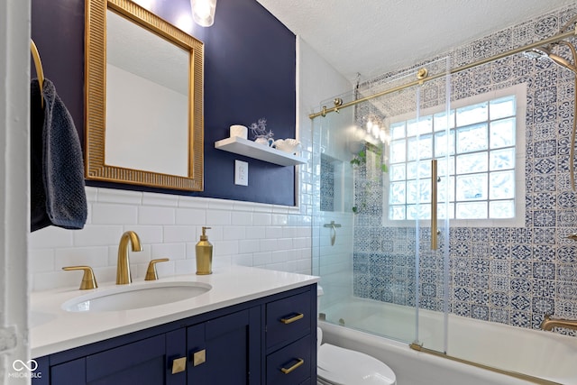 5259 Broadway St, Indianapolis, IN 46220 - bathroom with tile walls, toilet, combined bath / shower with glass door, vanity, and a textured ceiling