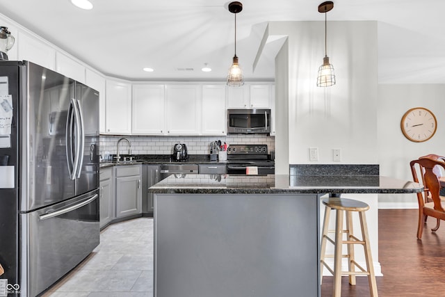 350 N Meridian St Unit 705, Indianapolis, IN 46204 - kitchen featuring stainless steel appliances, a peninsula, dark stone countertops, a breakfast bar, and decorative backsplash