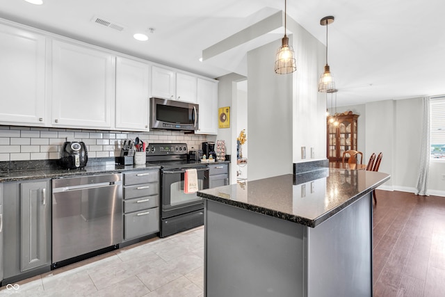 350 N Meridian St Unit 705, Indianapolis, IN 46204 - kitchen featuring stainless steel appliances, tasteful backsplash, dark stone countertops, white cabinets, and hanging light fixtures