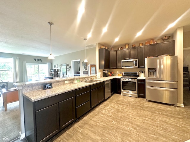 4209 Switchgrass Way, Indianapolis, IN 46237 - kitchen with stainless steel appliances, a peninsula, a sink, dark brown cabinets, and pendant lighting
