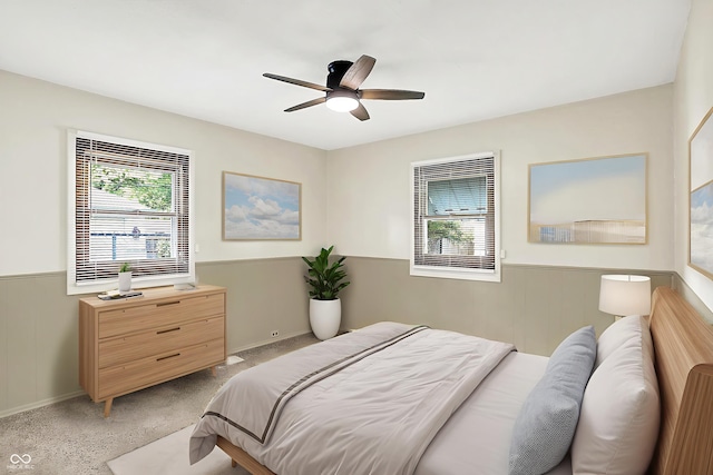 1868 N Hawthorne Ln, Indianapolis, IN 46218 - bedroom featuring multiple windows, a wainscoted wall, light colored carpet, and a ceiling fan