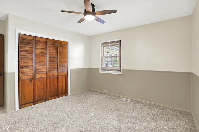 1868 N Hawthorne Ln, Indianapolis, IN 46218 - unfurnished bedroom with a wainscoted wall, carpet, a closet, and a ceiling fan
