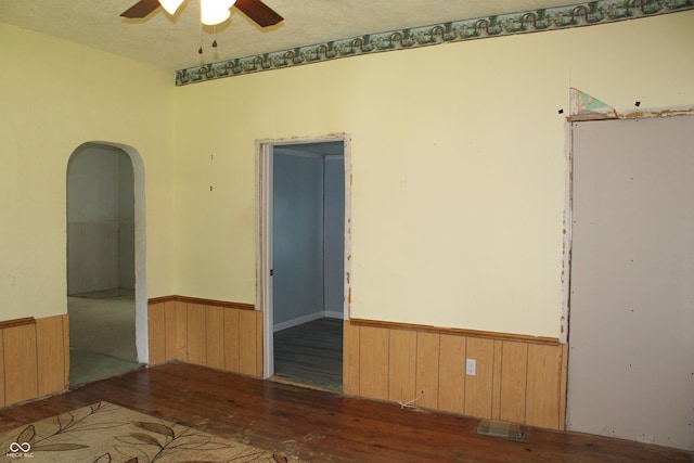 202 S Church St, Brooklyn, IN 46111 - empty room featuring a wainscoted wall, a ceiling fan, arched walkways, wood walls, and wood finished floors