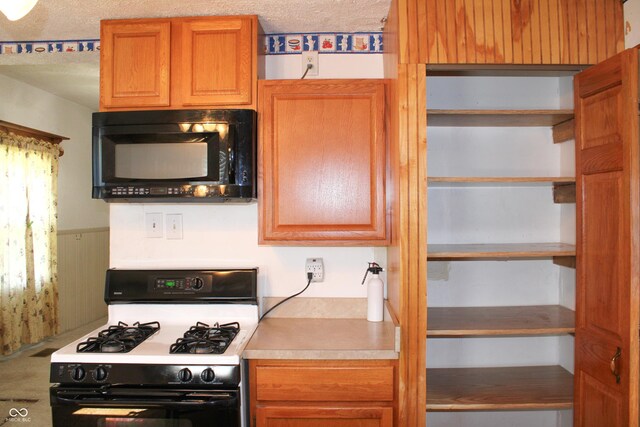 202 S Church St, Brooklyn, IN 46111 - kitchen featuring gas stove, black microwave, open shelves, wood walls, and a textured ceiling