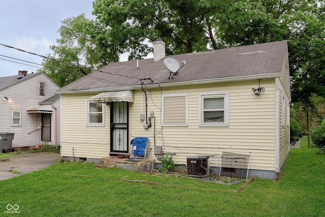 3338 Orchard Ave, Indianapolis, IN 46218 - rear view of house with central AC unit, a chimney, and a lawn