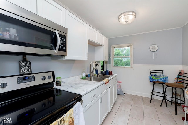 3338 Orchard Ave, Indianapolis, IN 46218 - kitchen featuring stainless steel appliances, a sink, white cabinetry, light tile patterned floors, and crown molding