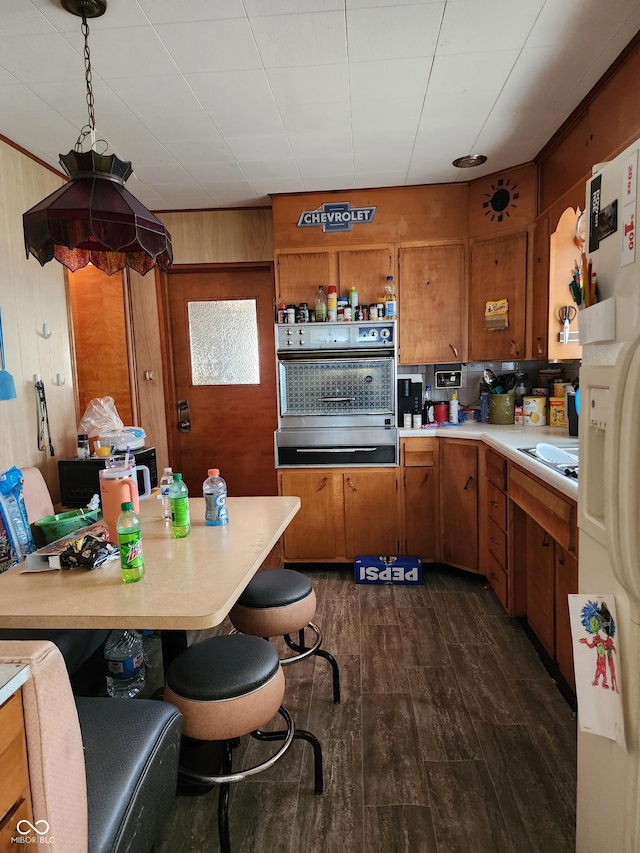 621 E 31st St, Anderson, IN 46016 - kitchen with wall oven, brown cabinetry, light countertops, dark wood-style flooring, and wood walls