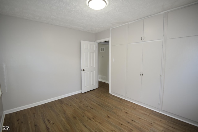 1902 N Colorado Ave, Indianapolis, IN 46218 - unfurnished bedroom with a textured ceiling, wood finished floors, a closet, and baseboards