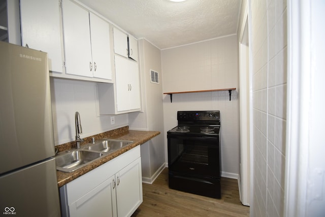 1902 N Colorado Ave, Indianapolis, IN 46218 - kitchen featuring black electric range oven, freestanding refrigerator, a sink, a textured ceiling, and white cabinets