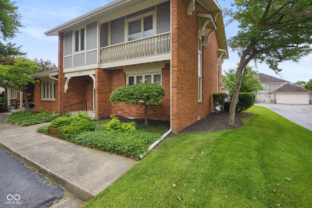 3975 Offshore Dr, Columbus, IN 47203 - view of front of house with brick siding, a front lawn, a balcony, and a detached garage