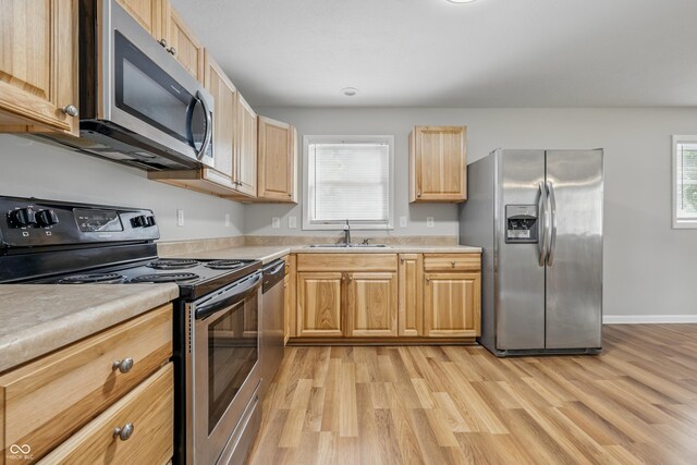 420 Vista Dr, Carmel, IN 46280 - kitchen with stainless steel appliances, a sink, light wood-type flooring, light countertops, and light brown cabinetry