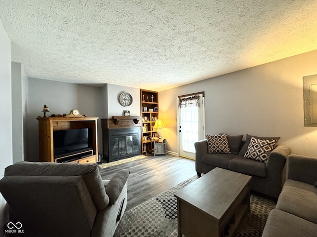 7445 Melanie Ln, Indianapolis, IN 46217 - living area featuring wood finished floors, a glass covered fireplace, a textured ceiling, and baseboards
