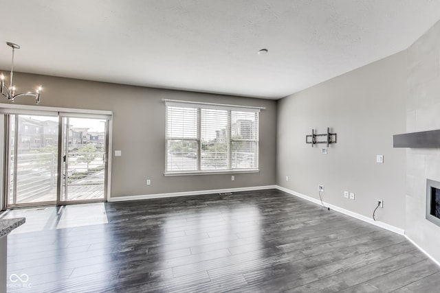 13050 Grand Vue Dr, Carmel, IN 46032 - unfurnished living room featuring a chandelier, a tile fireplace, dark wood-type flooring, and baseboards