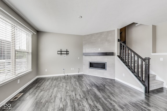 13050 Grand Vue Dr, Carmel, IN 46032 - unfurnished living room featuring a tiled fireplace, dark wood-style flooring, stairway, and baseboards