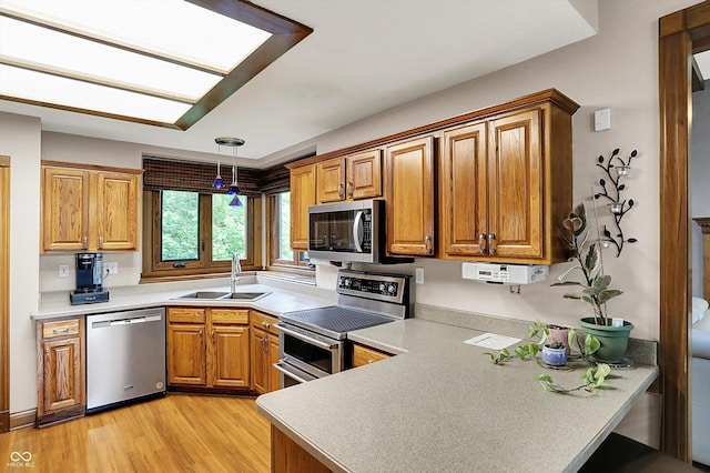 1850 Longest Dr, Franklin, IN 46131 - kitchen with stainless steel appliances, a sink, a peninsula, brown cabinets, and light wood-style flooring