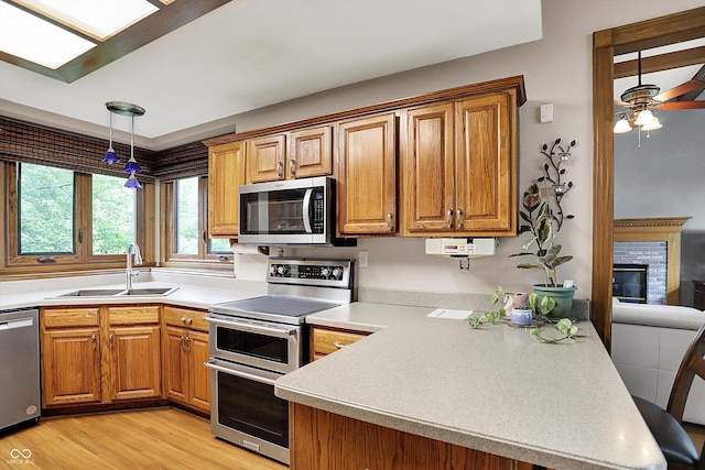 1850 Longest Dr, Franklin, IN 46131 - kitchen with appliances with stainless steel finishes, a sink, a peninsula, light wood-style flooring, and light countertops