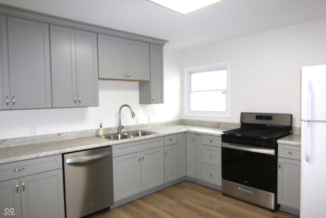 1021 Harney Dr, Lebanon, IN 46052 - kitchen featuring stainless steel appliances, a sink, gray cabinetry, light wood-style flooring, and light countertops