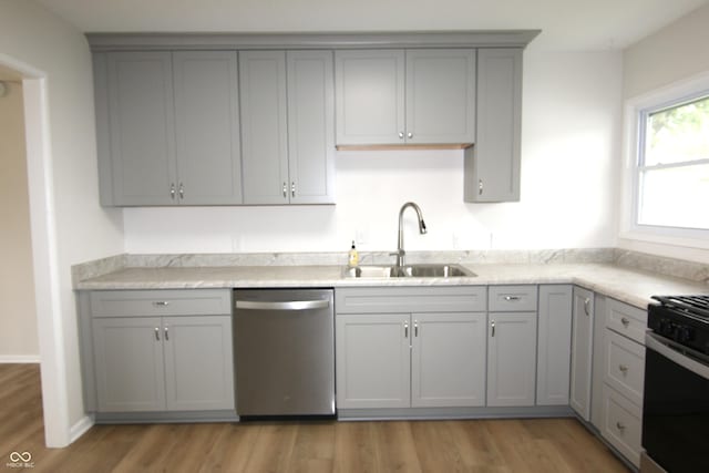 1021 Harney Dr, Lebanon, IN 46052 - kitchen with stainless steel dishwasher, gray cabinetry, a sink, light wood finished floors, and gas range oven