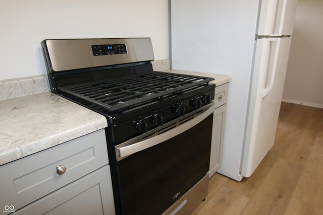 1021 Harney Dr, Lebanon, IN 46052 - kitchen with stainless steel range with gas cooktop, light wood-type flooring, light countertops, and freestanding refrigerator