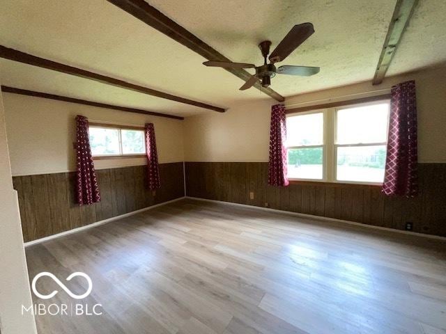 1998 Crescent St, Franklin, IN 46131 - spare room with wainscoting, beamed ceiling, wood finished floors, wooden walls, and a ceiling fan