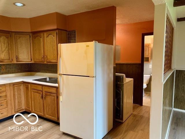 1998 Crescent St, Franklin, IN 46131 - kitchen featuring freestanding refrigerator, light wood-style floors, washer / dryer, brown cabinetry, and a wainscoted wall